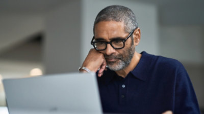 A man with his hand on his chin looking at a computer screen.