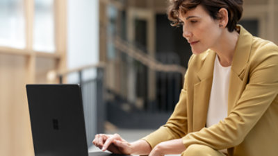  A woman in a yellow suit using a laptop.