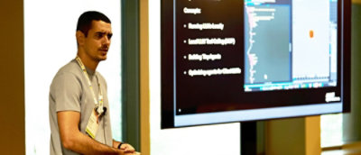 A man standing in front of a computer screen displaying text.