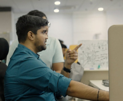 A man in a blue shirt pointing at a computer screen.