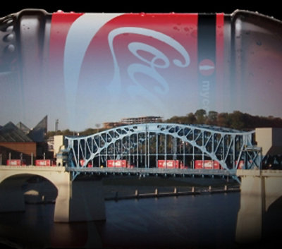 Eine rote Flasche mit einem weißen Logo vor einer Brücke.