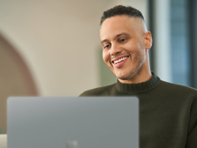 Ein Mann mit rasiertem Kopf, der auf einen Laptop lächelt