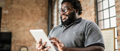 A man smiling while holding a tablet.