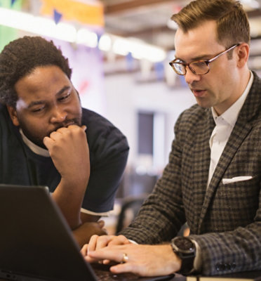 Two people talking to each other while looking at the screen.