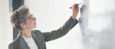 A woman teaching while writing on the white board