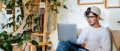 A man sitting on a couch using a laptop.