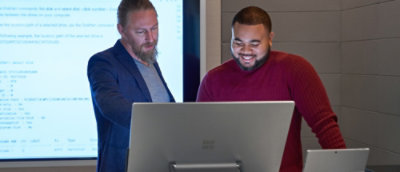 A man in a suit looking at a laptop.