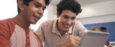 Student and educator use a tablet together in a classroom, engaging with interactive learning content.