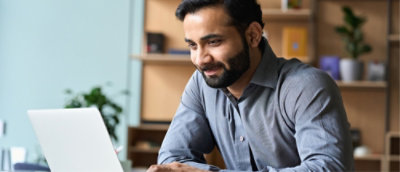Person works on a laptop at a desk, focused on digital tasks in a modern office setting.