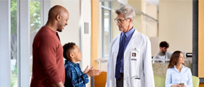 A man and a boy talking to a doctor.
