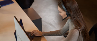 Przedstawicielka obsługi klienta w zestawie słuchawkowym pracująca na komputerze.