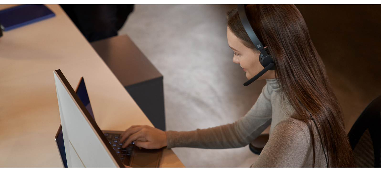 Customer service representative working on a computer while wearing a headset.