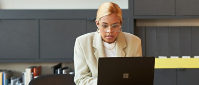 夜、窓越しに見えるぼんやりとした街の明かりを背景に、タブレットの画面を見る女性。