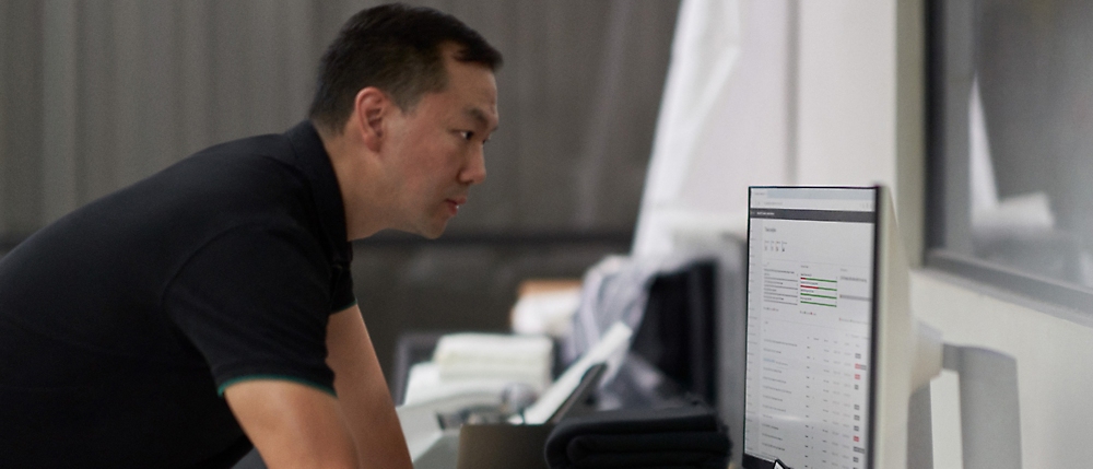 Hombre concentrado en la pantalla de un equipo en un entorno de oficina moderna.