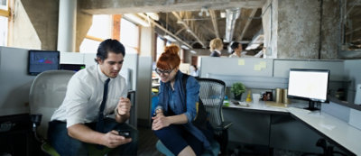 שני עמיתים במשרד יושבים ומביטים בטלפון חכם יחד.