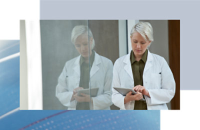 A person in white lab coats using a tablet