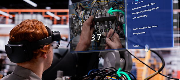 一名技术人员戴着虚拟现实头戴显示设备，一边参考数字叠加指南，一边在配电盘上工作。