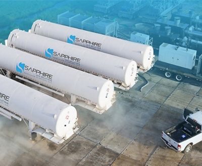 Four large white 'SAPPHIRE'-branded industrial tanks on a concrete surface with a pickup truck nearby in an outdoor facility.