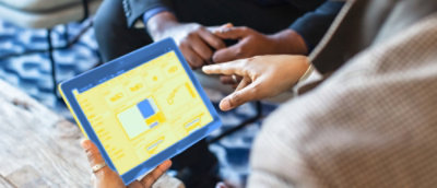 A close-up of a person's hands pointing at a tablet.