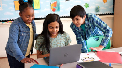 Three students gathered around a laptop working on an activity together.
