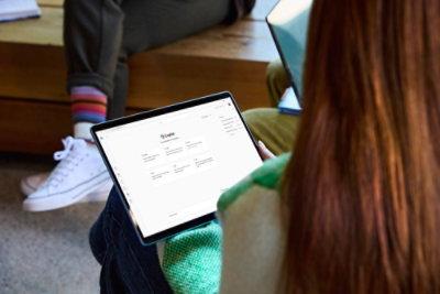 Person using a tablet displaying a Copilot interface while seated.