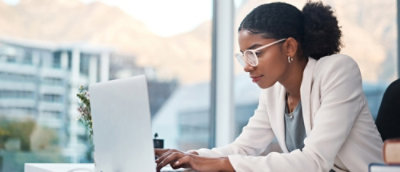 A women wearing glasses, working on a laptop.