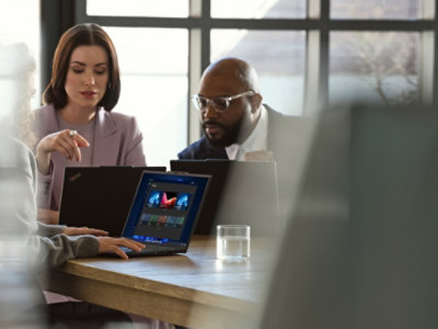 A group of people sitting at a table looking at a laptop.