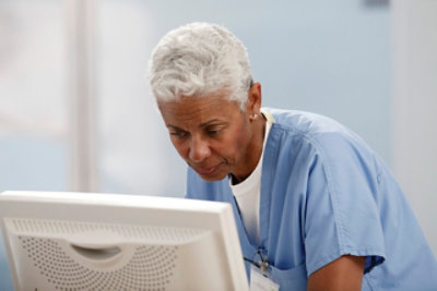 Eine Frau in einem weißen Kittel, die auf ein Tablet blickt.