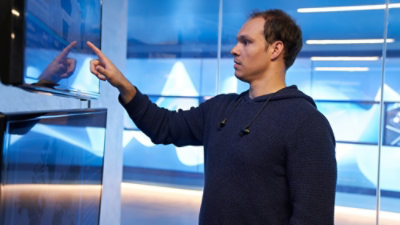 A person pointing at a screen with a blue background.