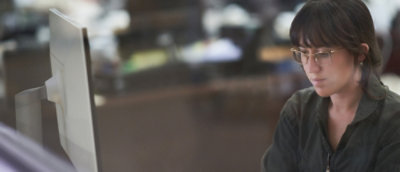 A woman wearing a glasses and working on a laptop