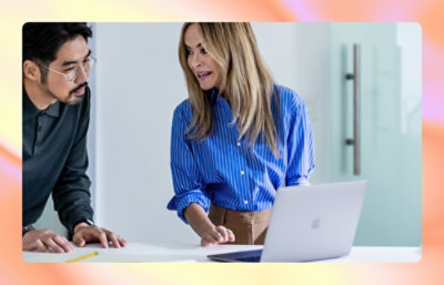 A man and a woman sitting together and looking at a laptop on a table.