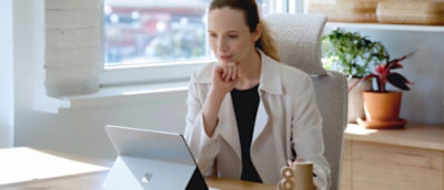 A woman sitting at a desk looking at a laptop.