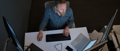 A person sitting at a desk using a keyboard and computer.