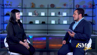 A man and woman sitting in front of a glass shelf.