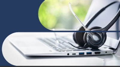 耳機放在打開的膝上型電腦鍵盤上，透過圓形切口可以看到模糊的綠色自然背景。