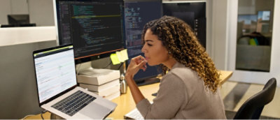 Femme assise à un bureau regardant un écran d’ordinateur.