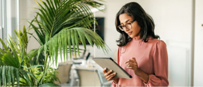 Femme portant des lunettes et tenant une tablette.