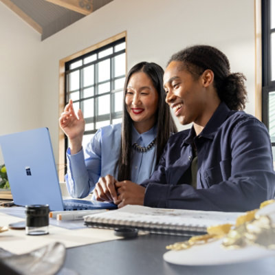 Deux professionnels qui collaborent sur un bureau tout en travaillant sur un ordinateur portable dans un environnement de bureau moderne.