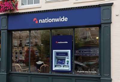 A close-up of a bank ATM machine with a blue sign displaying white text including Nationwide and A good way to bank.