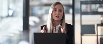 A woman with long hair sitting at a table with a laptop.