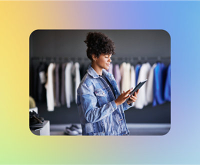 A woman in a denim jacket is using a tablet in a clothing store