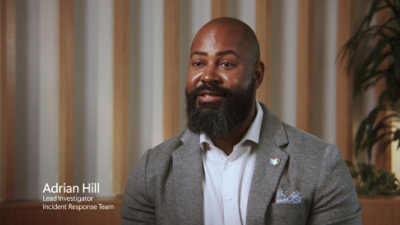 A man with a beard wearing a suit, accompanied by text that reads Adrian Hill, Lead Investigator, Incident Response Team.