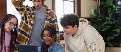  3 人の女性が一緒に座り、タブレット デバイスで情報を共有しながら会話を交わしている。