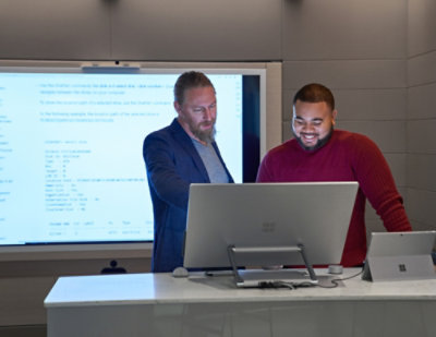 Two persons smiling and looking to laptop screen