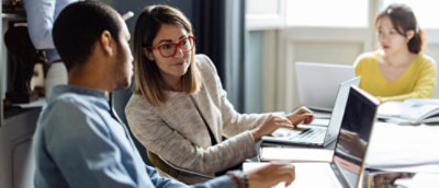 A women and a man seeing laptop screen in office desk.
