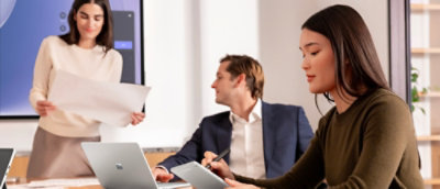 A group of people in a meeting room with various objects visible.
