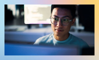 A man in glasses looking at a computer screen.