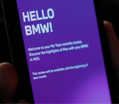 Close-up of a smartphone screen displaying a welcome message from a BMW service with text about a monthly review.