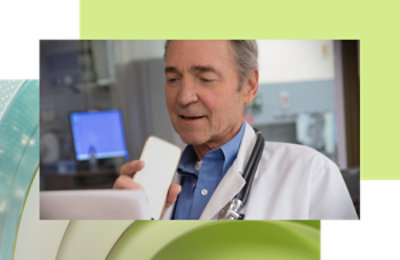 Eine ärztliche Fachperson in einem weißen Kittel, die ein Mobiltelefon hält.