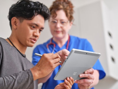 Lekar i medicinska sestra gledaju u tablet.